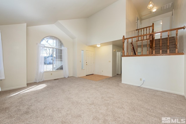 unfurnished living room featuring light carpet and high vaulted ceiling