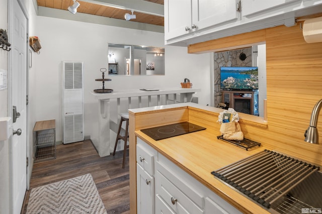 kitchen with white cabinetry, black electric stovetop, wooden ceiling, dark hardwood / wood-style floors, and beam ceiling