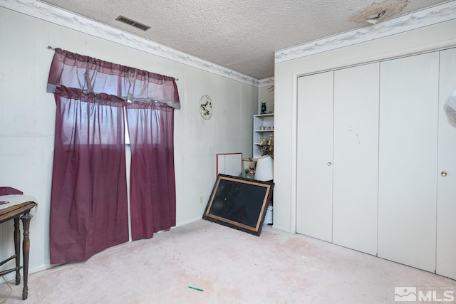 bedroom with light carpet, a textured ceiling, and a closet