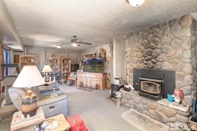 living room featuring carpet flooring, ceiling fan, a textured ceiling, and a wood stove