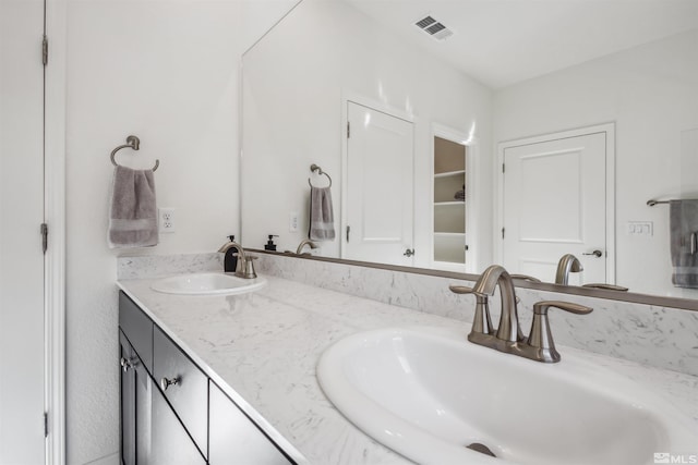 bathroom with double vanity, visible vents, and a sink