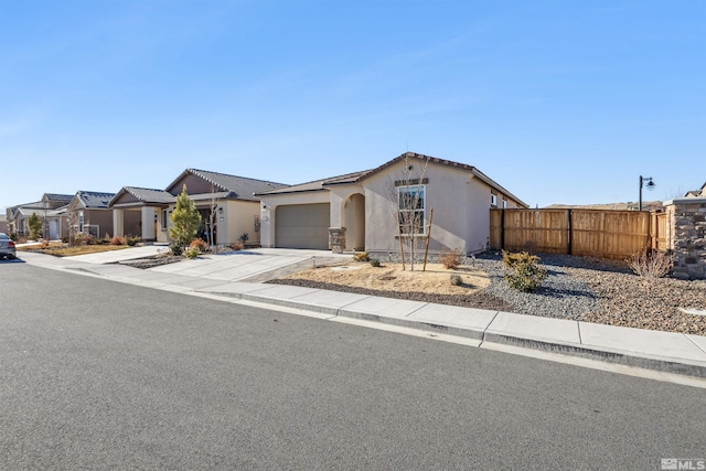 view of front of home featuring a garage, driveway, fence, and stucco siding