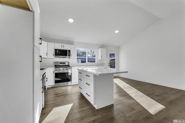 kitchen with dark hardwood / wood-style floors, appliances with stainless steel finishes, white cabinets, and a center island