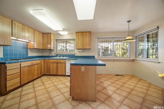 kitchen with kitchen peninsula, gas cooktop, sink, light tile patterned flooring, and tile counters