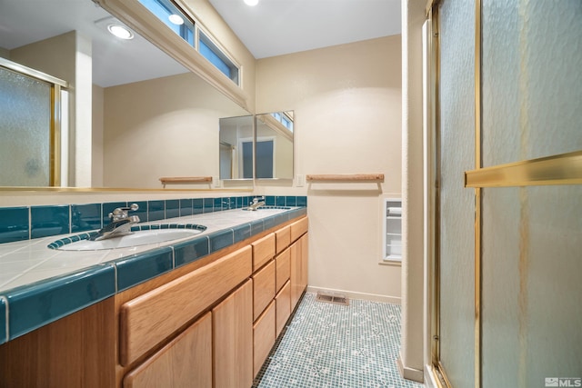 bathroom with tile patterned flooring, a shower with shower door, tasteful backsplash, and vanity