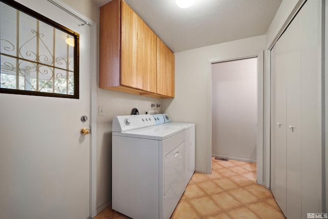 laundry area with light tile patterned flooring, separate washer and dryer, a textured ceiling, and cabinets