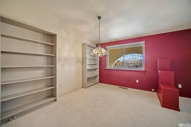 carpeted spare room with a notable chandelier