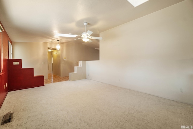 empty room with vaulted ceiling, ceiling fan, and light colored carpet