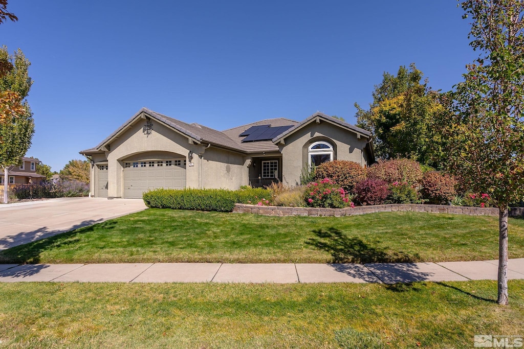 single story home featuring a garage, a front lawn, and solar panels