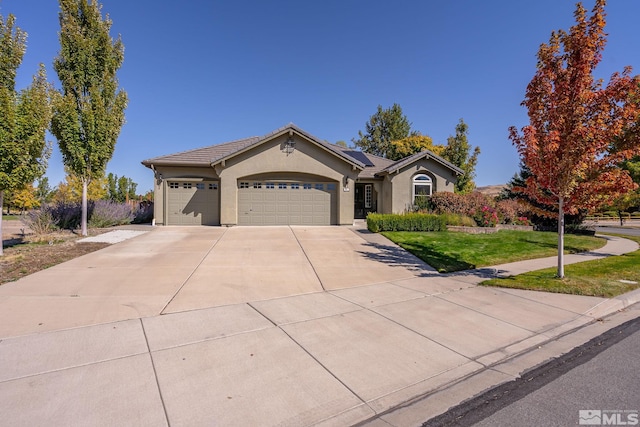 ranch-style home featuring a front lawn, solar panels, and a garage