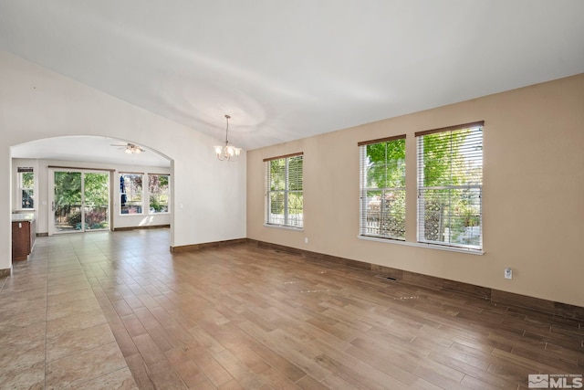 empty room featuring ceiling fan with notable chandelier and hardwood / wood-style floors