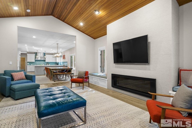 living room with light hardwood / wood-style floors, a chandelier, wood ceiling, and vaulted ceiling