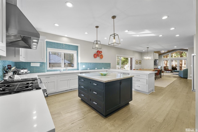 kitchen with pendant lighting, white cabinets, a kitchen island, a healthy amount of sunlight, and ventilation hood