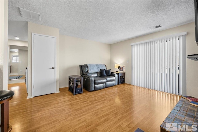 living room with a textured ceiling and light hardwood / wood-style floors