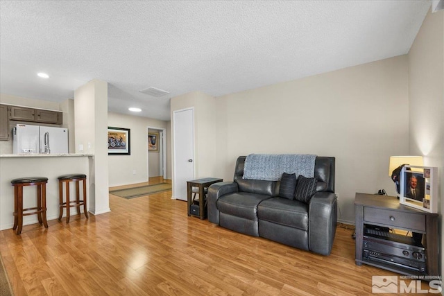 living room featuring a textured ceiling and light hardwood / wood-style floors