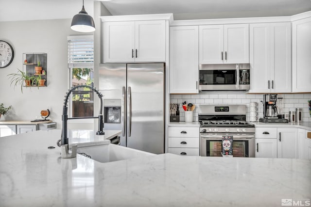 kitchen with stainless steel appliances, white cabinetry, hanging light fixtures, and light stone countertops