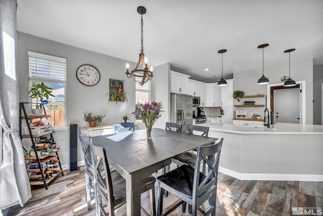 dining space with light hardwood / wood-style floors, sink, and an inviting chandelier