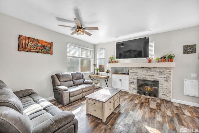 living room with a fireplace, ceiling fan, and dark wood-type flooring