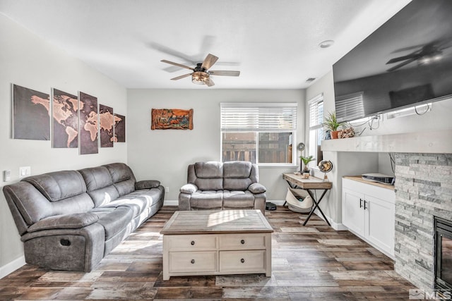 living room featuring ceiling fan, dark hardwood / wood-style floors, and a fireplace