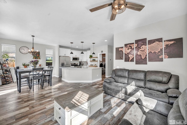 living room featuring ceiling fan with notable chandelier, sink, hardwood / wood-style flooring, and washer / clothes dryer