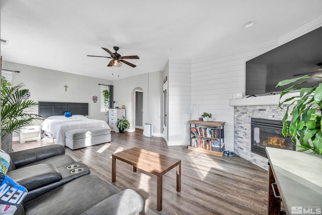 bedroom featuring ceiling fan, wood-type flooring, and a fireplace