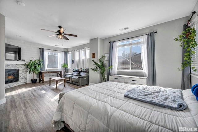 bedroom featuring ceiling fan, hardwood / wood-style flooring, and a fireplace