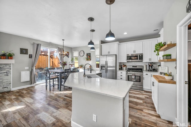 kitchen featuring stainless steel appliances, white cabinetry, and a kitchen island with sink