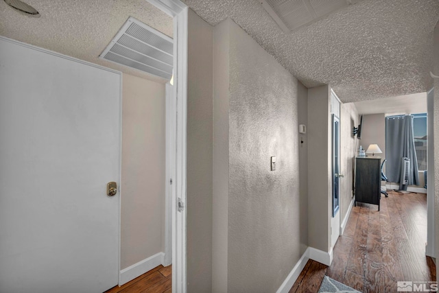 hallway with a textured ceiling and wood-type flooring