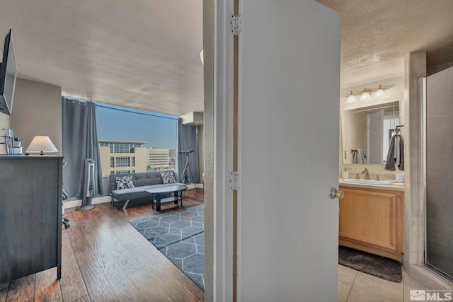 corridor featuring wood-type flooring, sink, and a textured ceiling