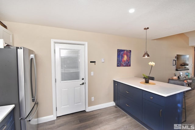 kitchen with dark hardwood / wood-style flooring, pendant lighting, kitchen peninsula, and stainless steel refrigerator