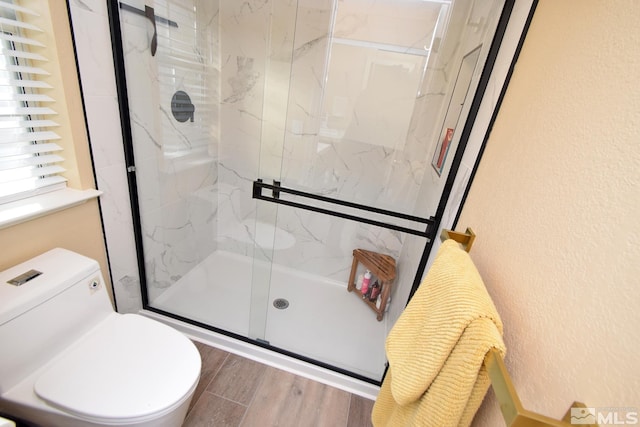 bathroom with wood-type flooring, an enclosed shower, and toilet