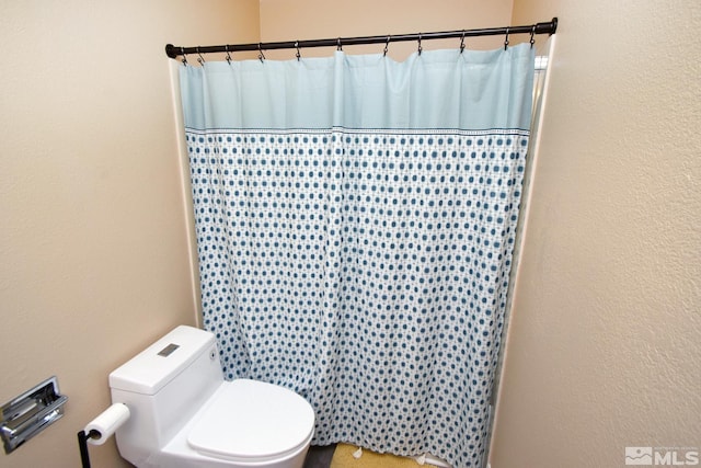 bathroom featuring toilet and walk in shower