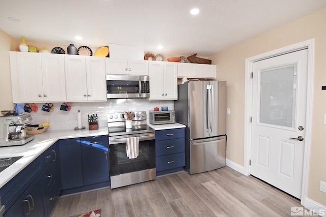 kitchen featuring white cabinetry, light hardwood / wood-style floors, stainless steel appliances, blue cabinetry, and backsplash