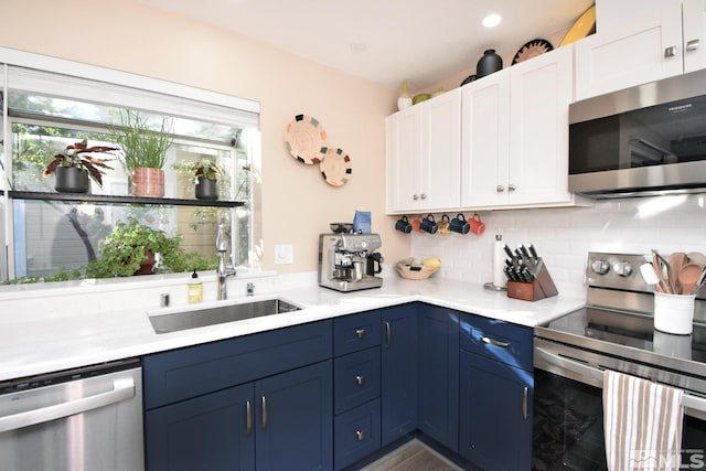 kitchen with backsplash, sink, stainless steel appliances, white cabinets, and blue cabinets