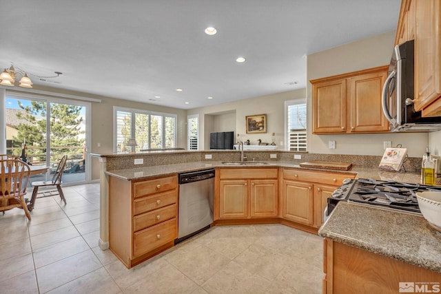 kitchen featuring appliances with stainless steel finishes, kitchen peninsula, light stone counters, and sink