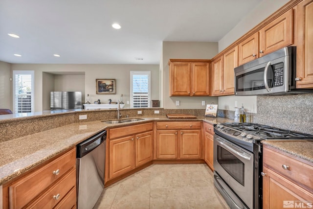 kitchen featuring stainless steel appliances, light stone counters, and sink