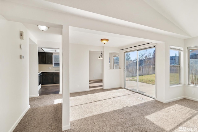 unfurnished living room with vaulted ceiling, an inviting chandelier, and carpet flooring