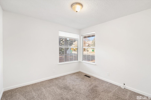 carpeted empty room featuring a textured ceiling