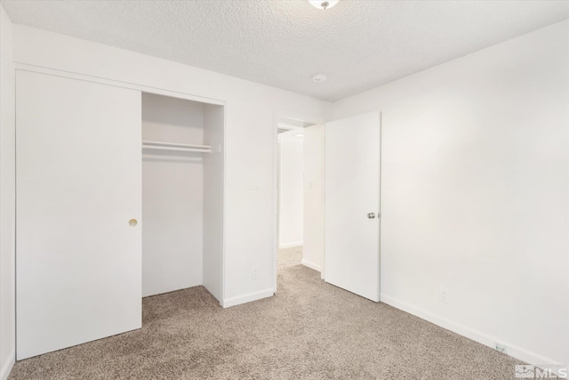 unfurnished bedroom with light colored carpet, a closet, and a textured ceiling