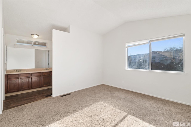 carpeted empty room with lofted ceiling and sink