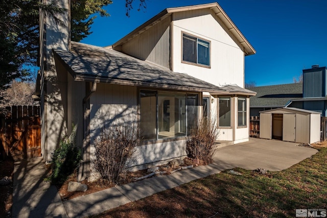 back of house with a storage unit and a patio