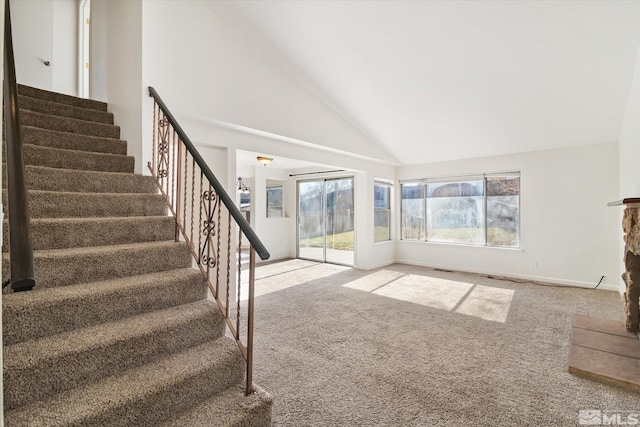 unfurnished living room featuring high vaulted ceiling and carpet floors