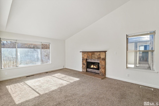 unfurnished living room featuring vaulted ceiling, carpet flooring, and a stone fireplace