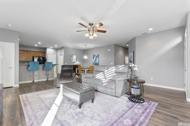 living room featuring ceiling fan and dark hardwood / wood-style floors