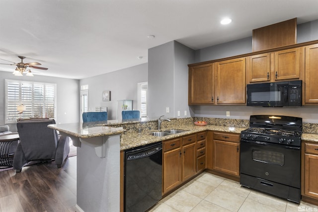 kitchen featuring plenty of natural light, sink, black appliances, and kitchen peninsula