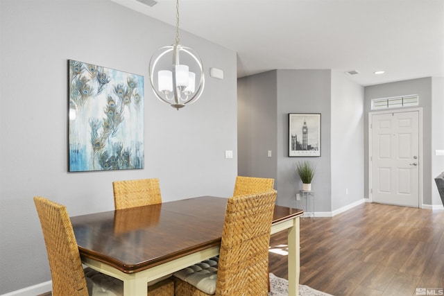 dining room with dark wood-type flooring and an inviting chandelier