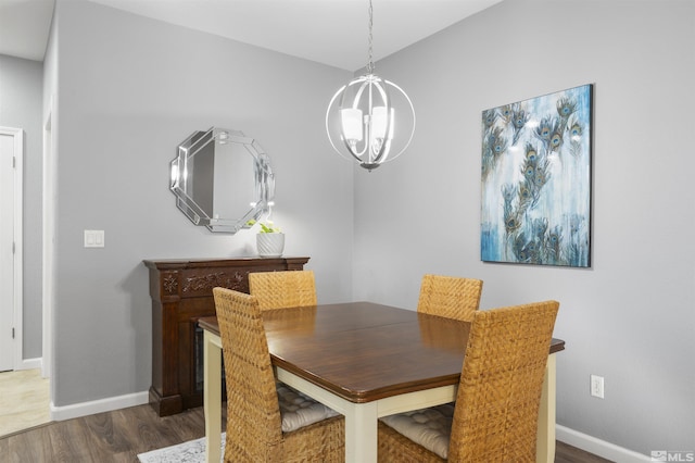 dining area with dark wood-type flooring and an inviting chandelier