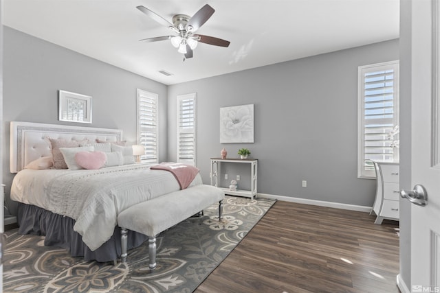 bedroom featuring ceiling fan, dark wood-type flooring, and multiple windows