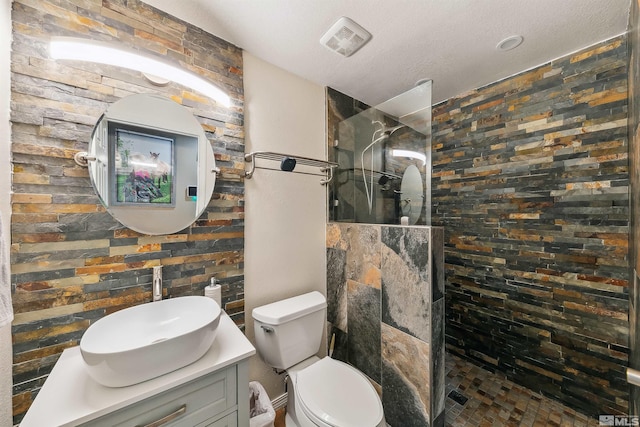 bathroom featuring vanity, a textured ceiling, toilet, and tiled shower