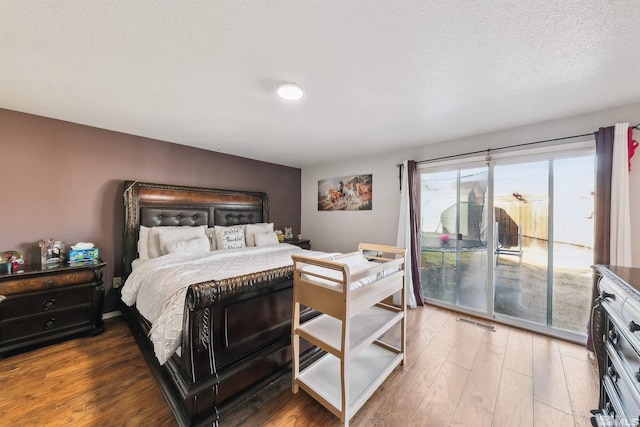 bedroom featuring wood-type flooring, access to exterior, and a textured ceiling